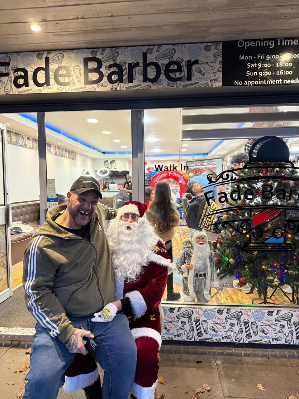 Santa outside the Fade Barbers shopfront with a customer, the shop busy behind them